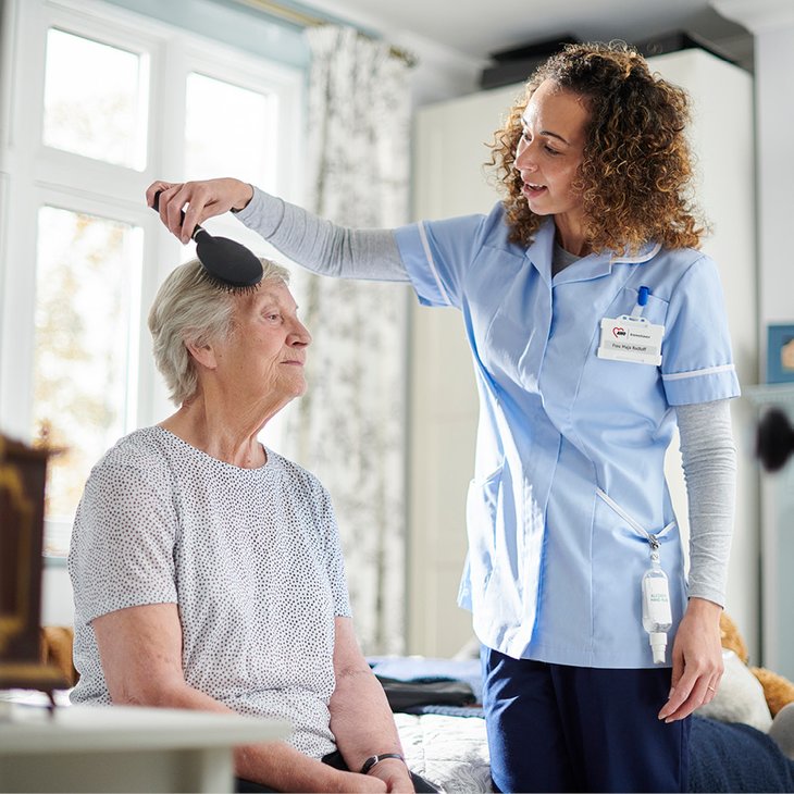 Das Foto zeigt eine Pflegefachkraft bei der Pflege einer älteren Frau